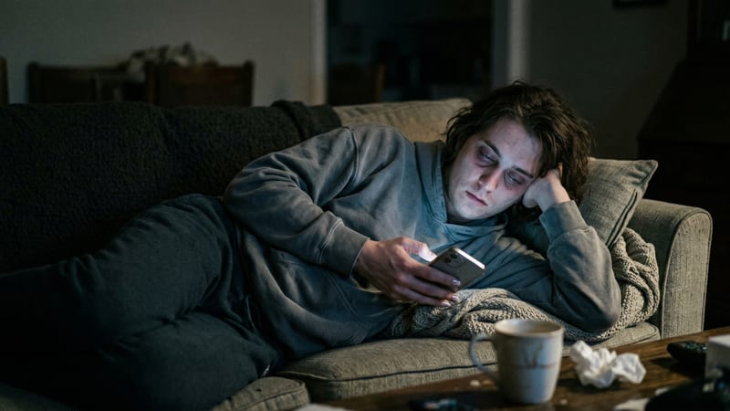 Person doomscrolling on a phone in a dark room — screen addiction stealing 70 days a year